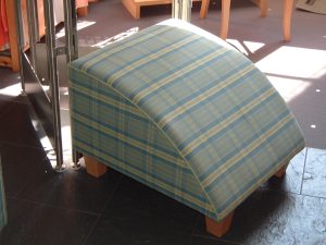 Moderner Fußhocker mit blau-grün kariertem Webstoff und hellen Holzfüßen
