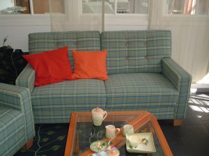 Gemütliches blau-grün kariertes Sofa mit roten Kissen