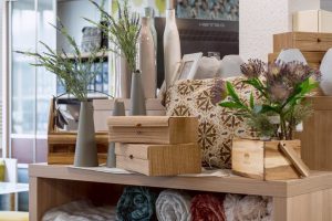 Blumen und Dekorationen auf einem Holzregal, stilvolle Raumgestaltung mit Vasen, Pflanzen und Textil.