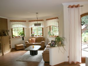 Helles Wohnzimmer mit Sofa, Couchtisch und Pflanzen bei Tageslicht.