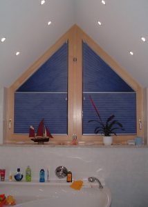 Dachfenster im Dachgeschoss mit blauen Plissees, Dekorationen und Pflanzenim maritimen Stil.