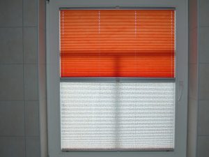 Zwei Plissees an einem Fenster in orange und weiß beige gemustert