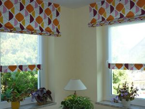 Blumen im Wohnzimmer vor bunten Flächenvorhängen, natürliche Lichtquelle, gemütliche Atmosphäre.