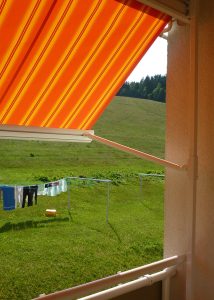 Fenstermarkise in Orange, schützt vor Sonne, ideal für Balkon oder Terrasse.