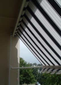 Markise mit schwarzen und weißen Streifen vor einem Balkon